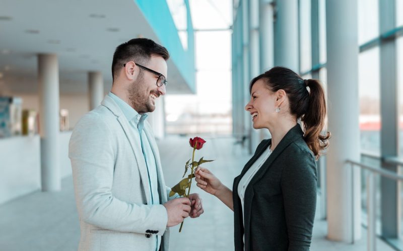 Businessman giving a rose to his pretty colleague.
